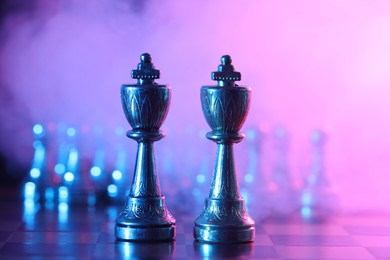 Photo of Kings on chessboard in color light, selective focus