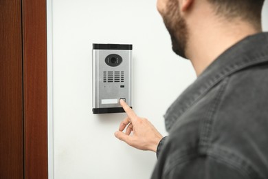 Photo of Man ringing intercom with camera in entryway, closeup