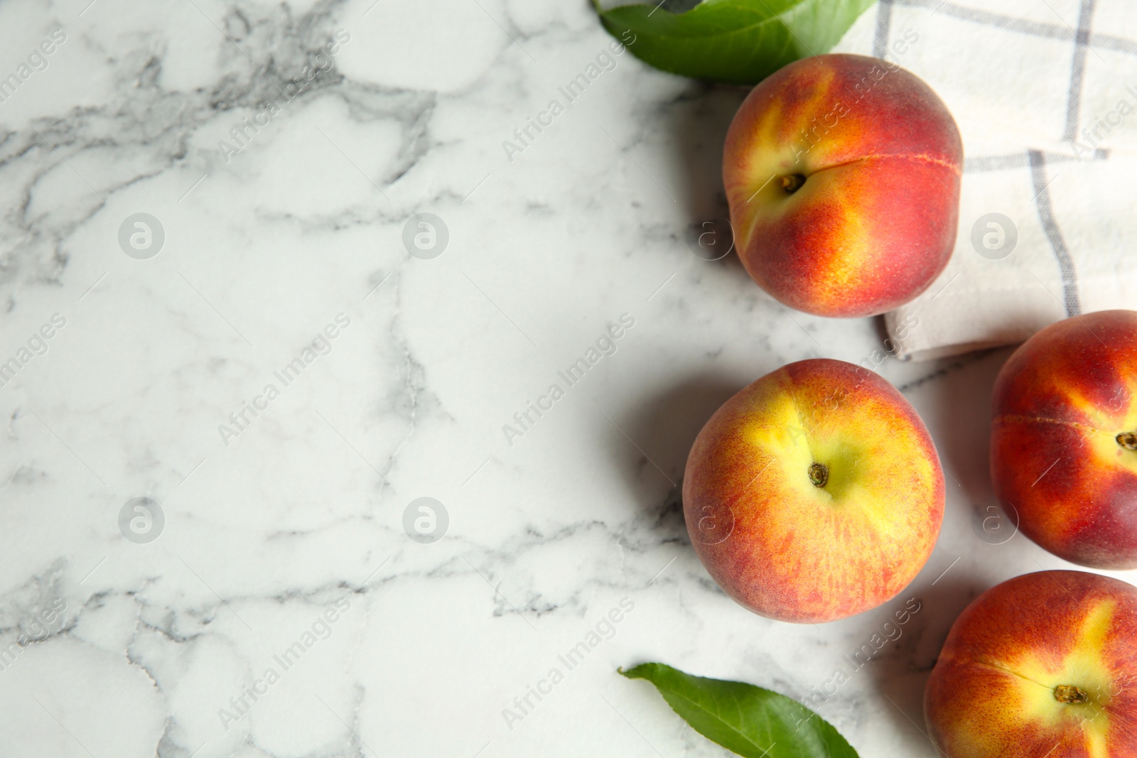 Photo of Fresh peaches, leaves and fabric on marble table, flat lay. Space for text