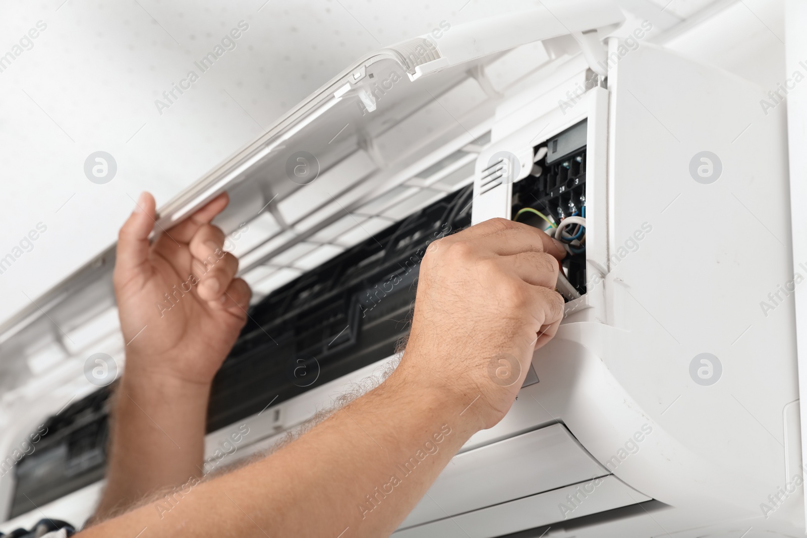 Photo of Male technician repairing air conditioner indoors