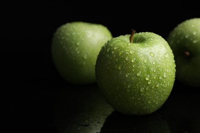 Photo of Green apples with water drops on black background, closeup
