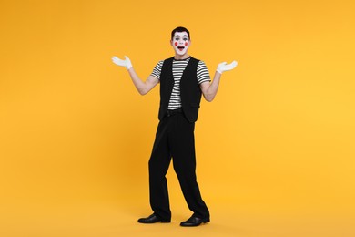 Photo of Mime artist making excited face on orange background