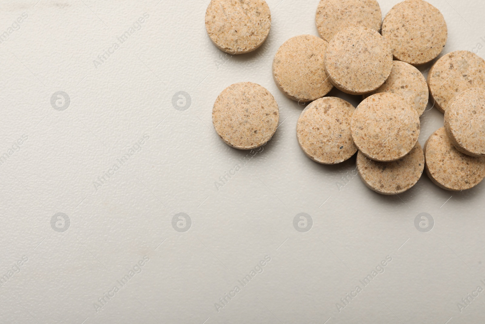 Photo of Dietary supplement pills on white table, flat lay. Space for text