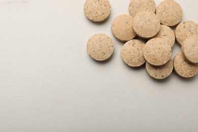 Photo of Dietary supplement pills on white table, flat lay. Space for text