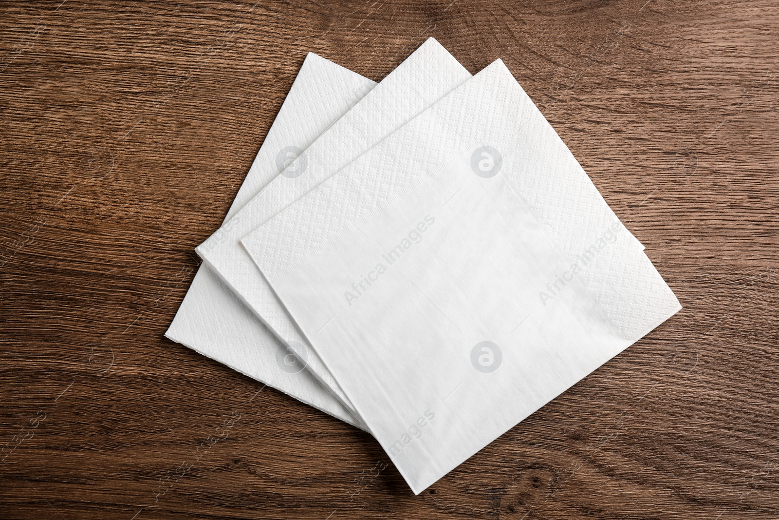 Photo of White clean paper tissues on wooden table, top view