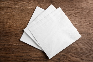 Photo of White clean paper tissues on wooden table, top view