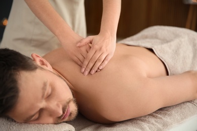 Handsome man receiving back massage in spa salon