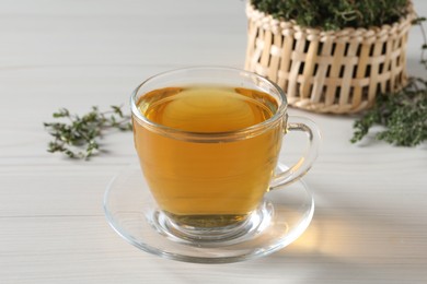 Aromatic herbal tea with thyme on white wooden table