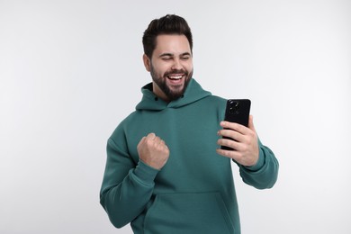 Photo of Happy young man using smartphone on white background