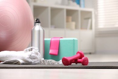 Many different sports equipment on floor indoors