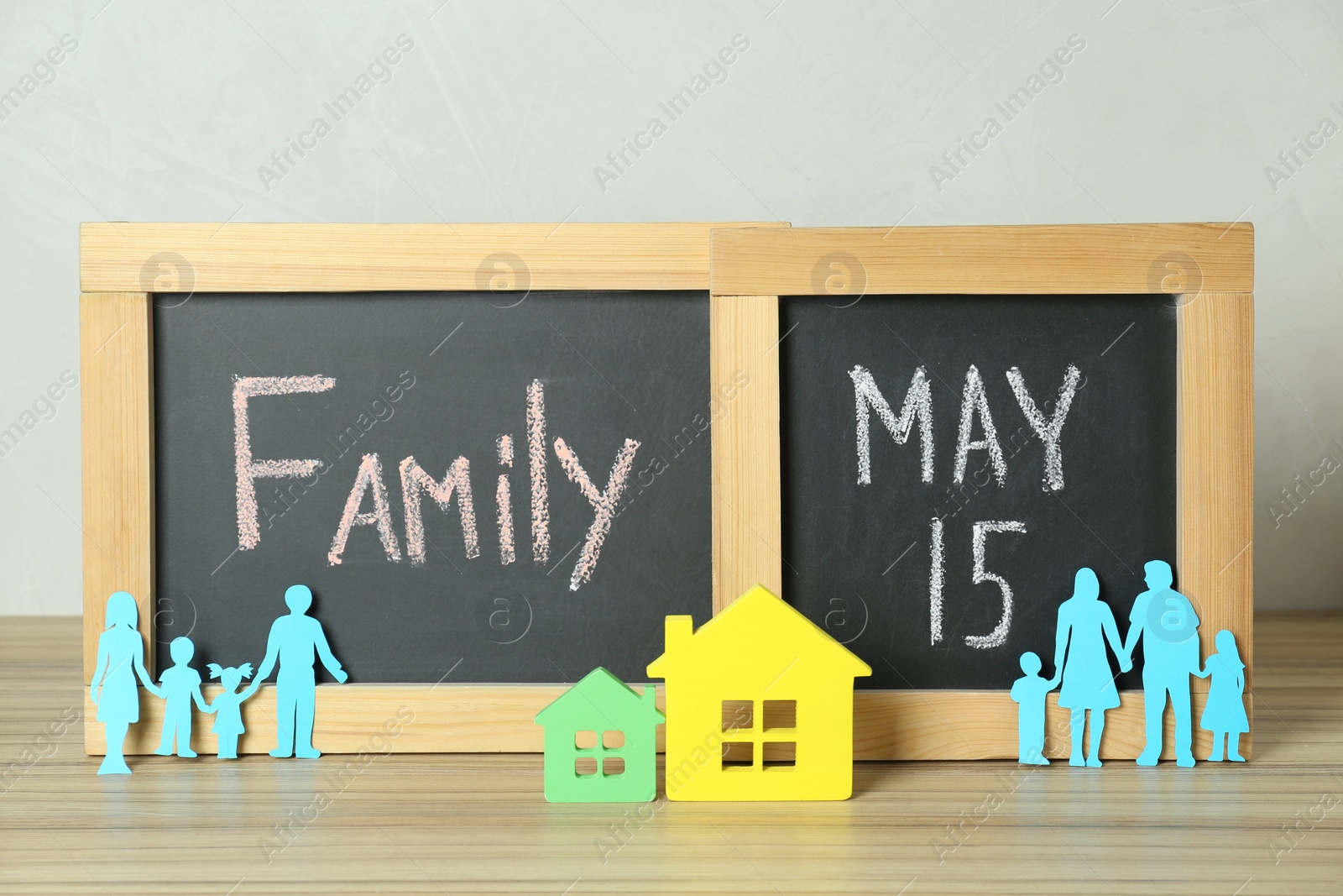 Photo of Happy Family Day. Blackboards, paper parents and their children near house models on wooden table