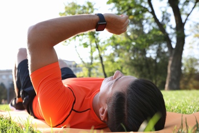 Photo of Man checking fitness tracker during training in park
