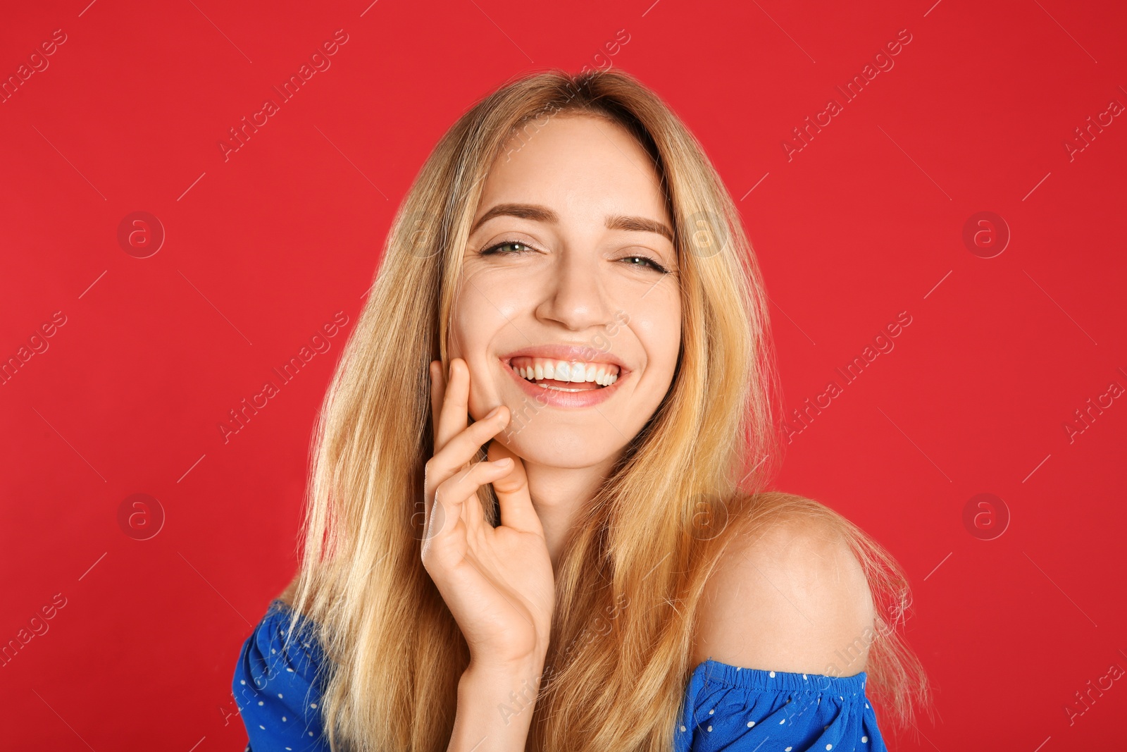 Photo of Portrait of beautiful young woman with blonde hair on red background