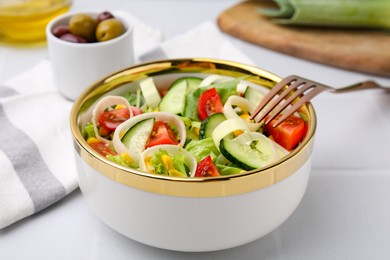 Bowl of tasty salad with leek, tomatoes and cucumbers on white tiled table, closeup