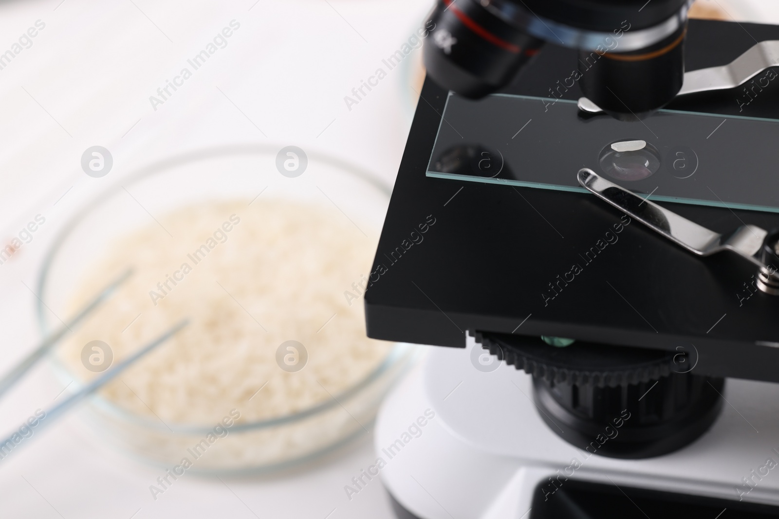Photo of Food quality control. Glass slide with rice grain under microscope on table, closeup