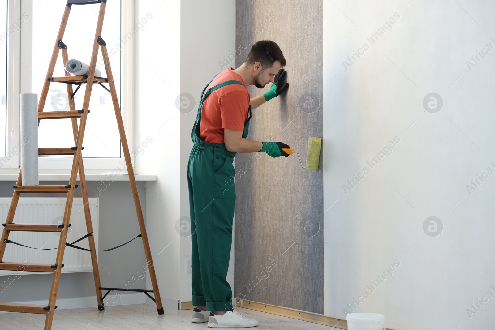 Photo of Man hanging stylish gray wallpaper in room