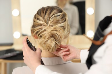 Hair styling. Professional hairdresser working with client indoors, closeup