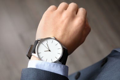 Businessman with stylish wrist watch indoors, closeup. Time management