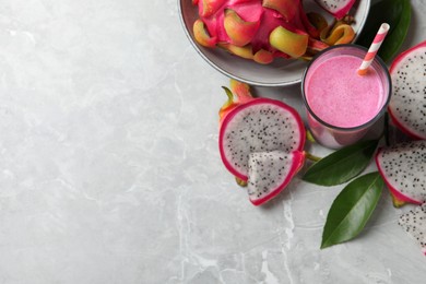 Photo of Glass of tasty pitahaya smoothie and fresh fruits on light grey table, flat lay. Space for text