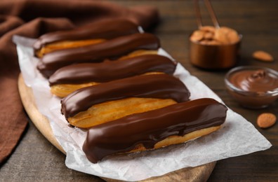 Delicious eclairs covered with chocolate on wooden table, closeup