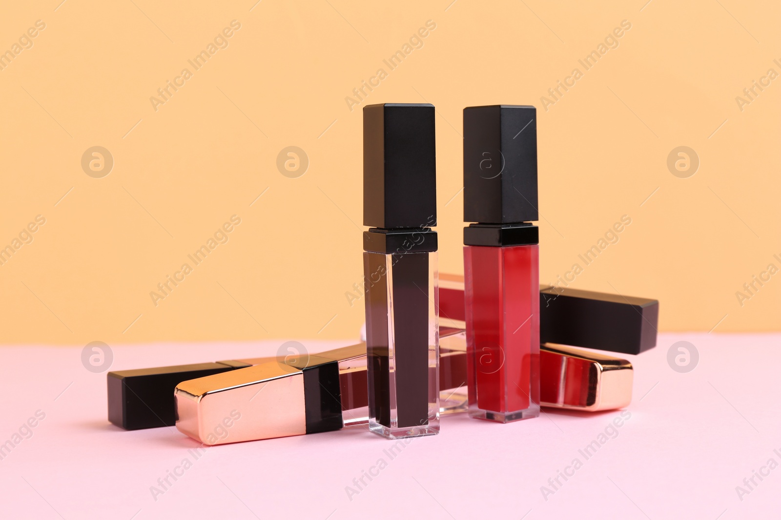 Photo of Many different lip glosses on color background