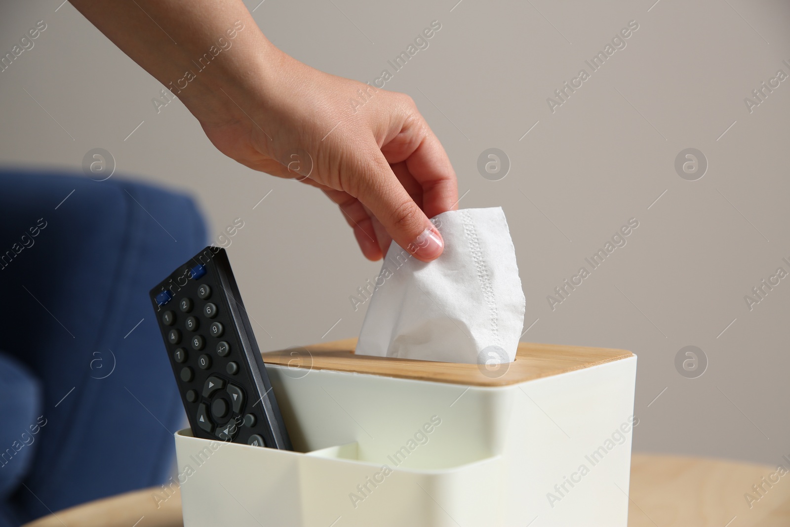 Photo of Woman taking paper tissue out of box on wooden table at home, closeup