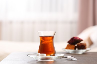 Photo of Glass with traditional Turkish tea and cookies on table indoors