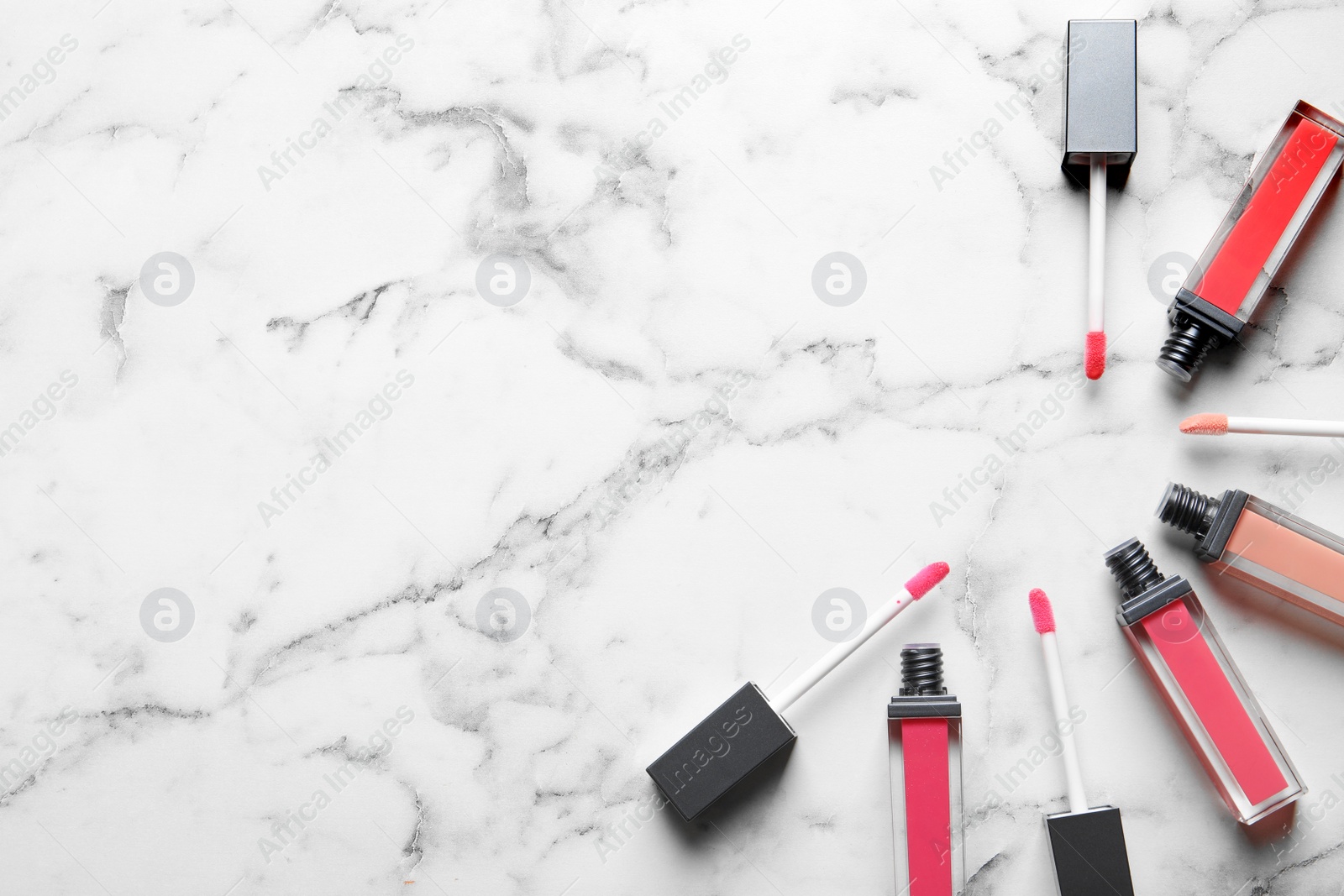 Photo of Liquid lipsticks on marble background, flat lay. Space for text