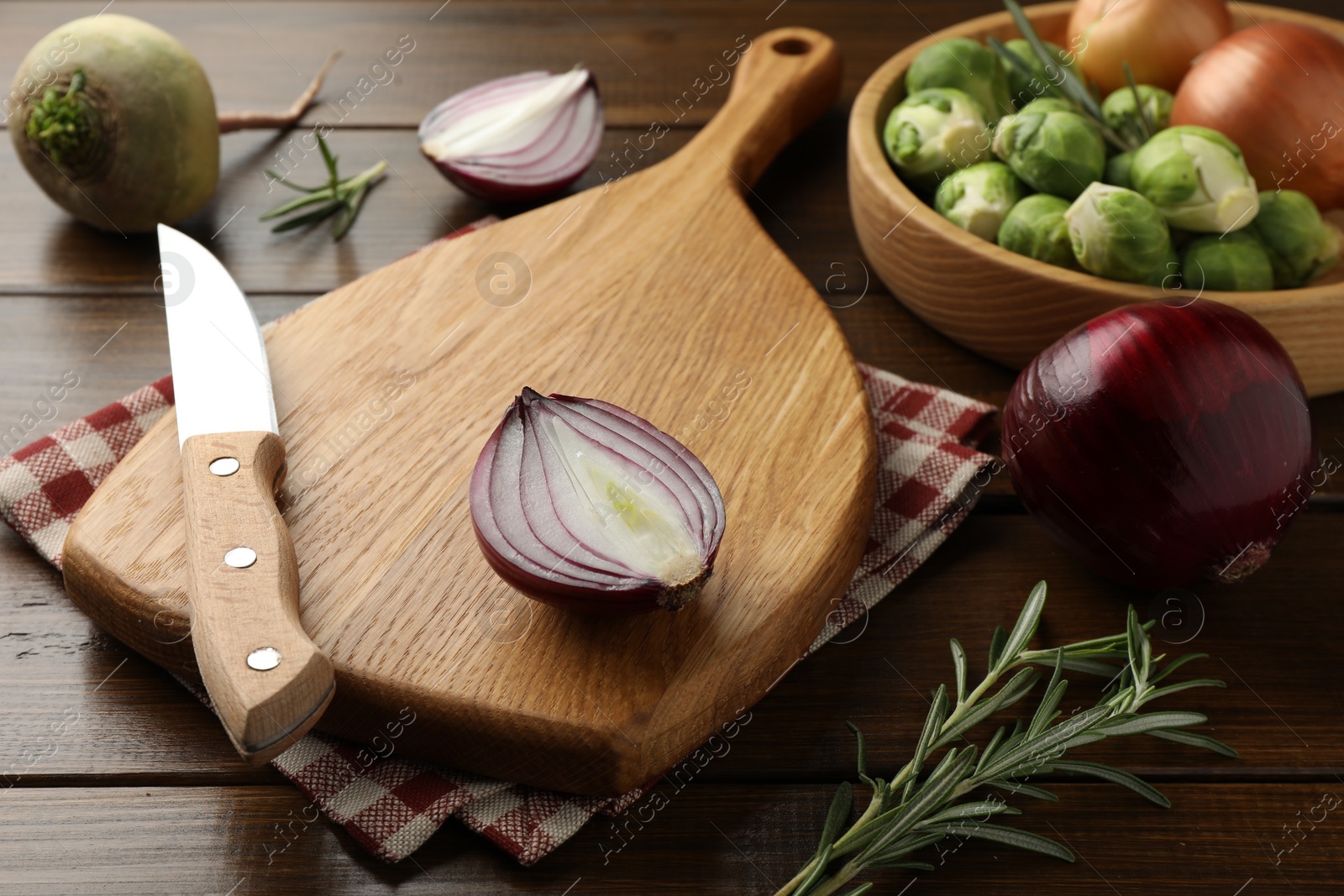 Photo of Cutting board with different vegetables, rosemary and knife on wooden table, closeup