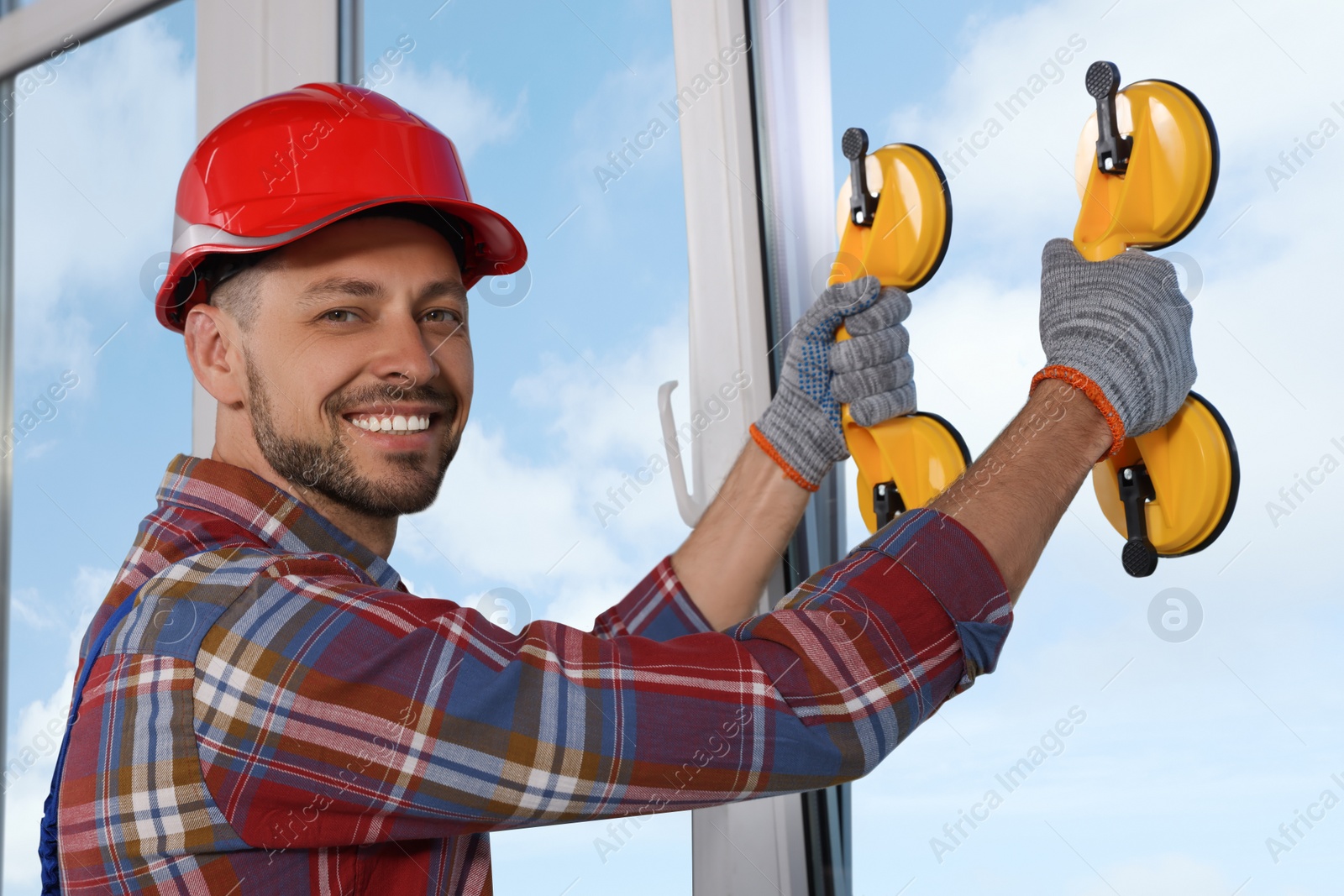 Photo of Worker using suction lifters during plastic window installation indoors