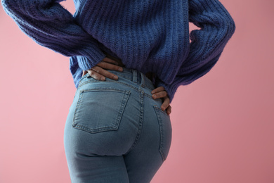 Woman wearing jeans on pink background, closeup