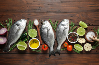 Flat lay composition with raw dorada fish on wooden table