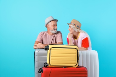 Photo of Senior couple with suitcases on color background. Vacation travel