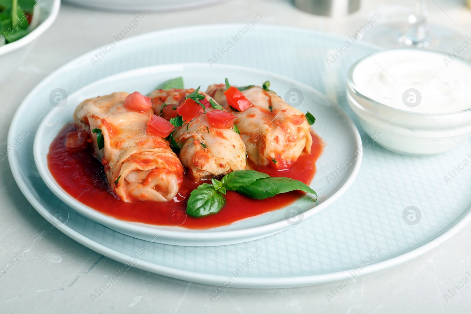 Photo of Plate with stuffed cabbage leaves in tomato sauce on table