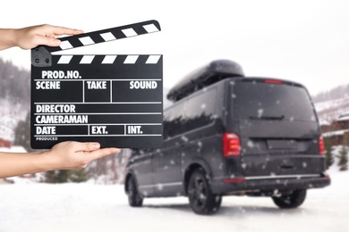 Image of Assistant  holding clapperboard and black car on snowy road, closeup. Cinema production 