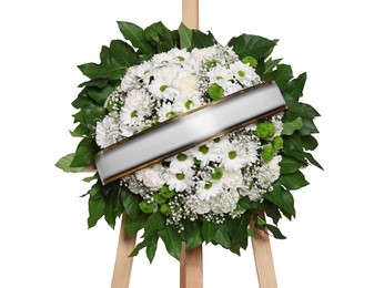 Funeral wreath of flowers with ribbon on wooden stand against white background