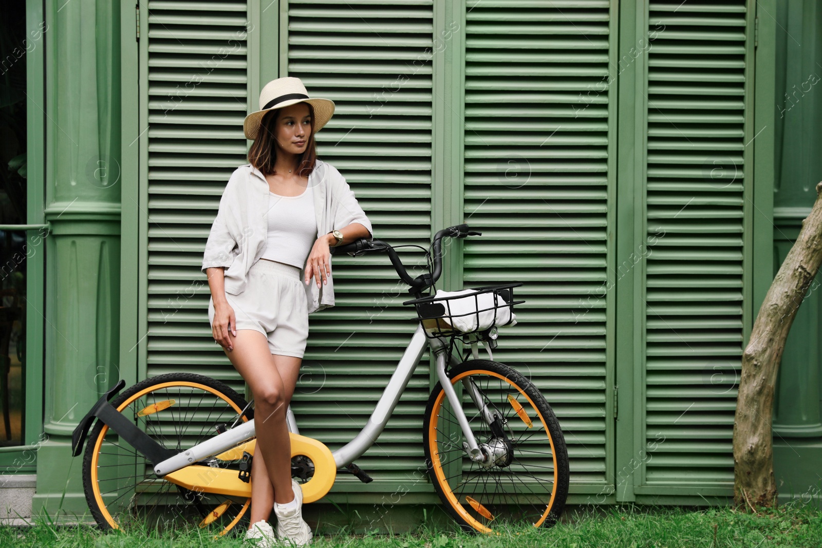 Photo of Beautiful young woman with bicycle near green wall outdoors. Space for text