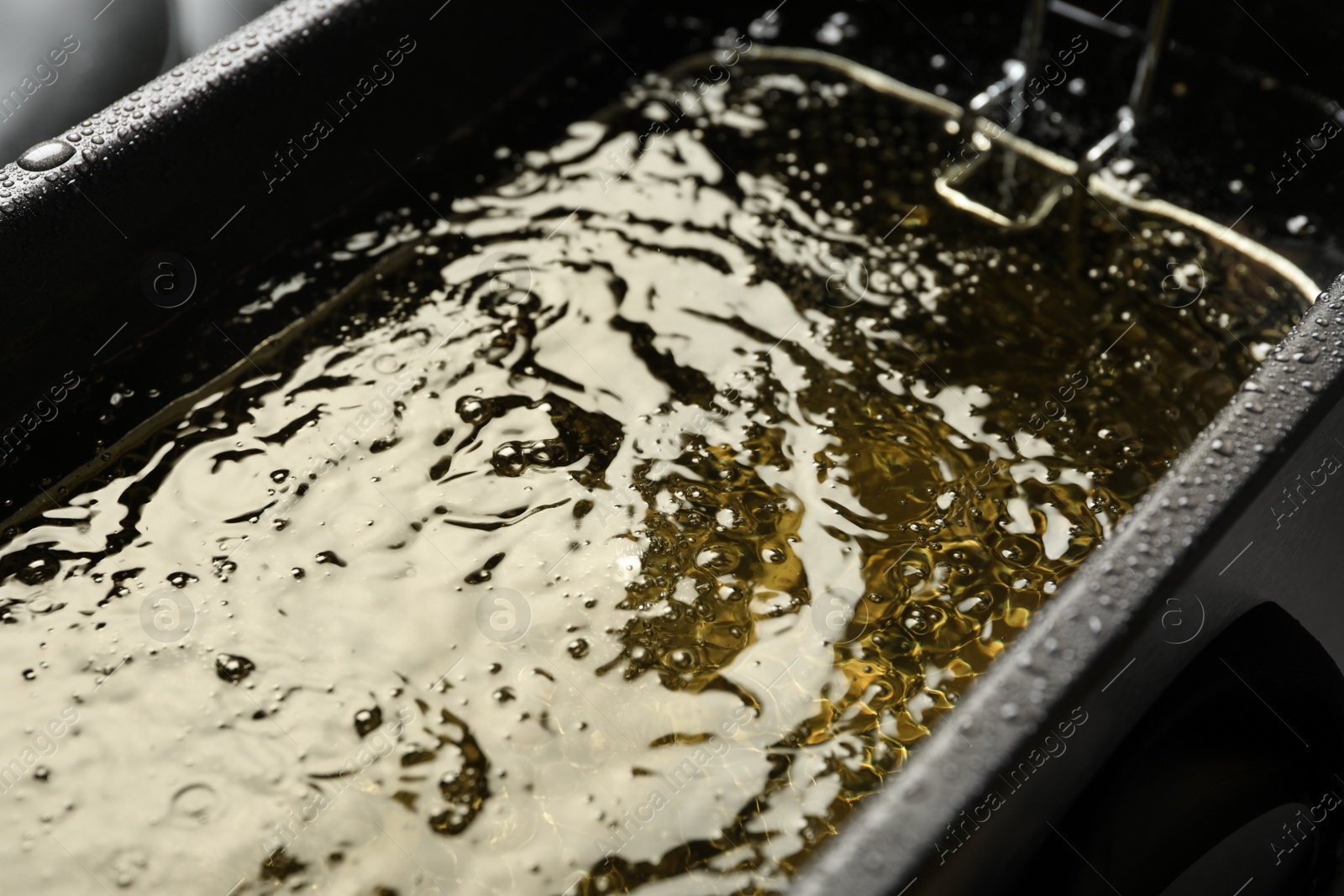 Photo of Hot cooking oil in deep fryer, closeup