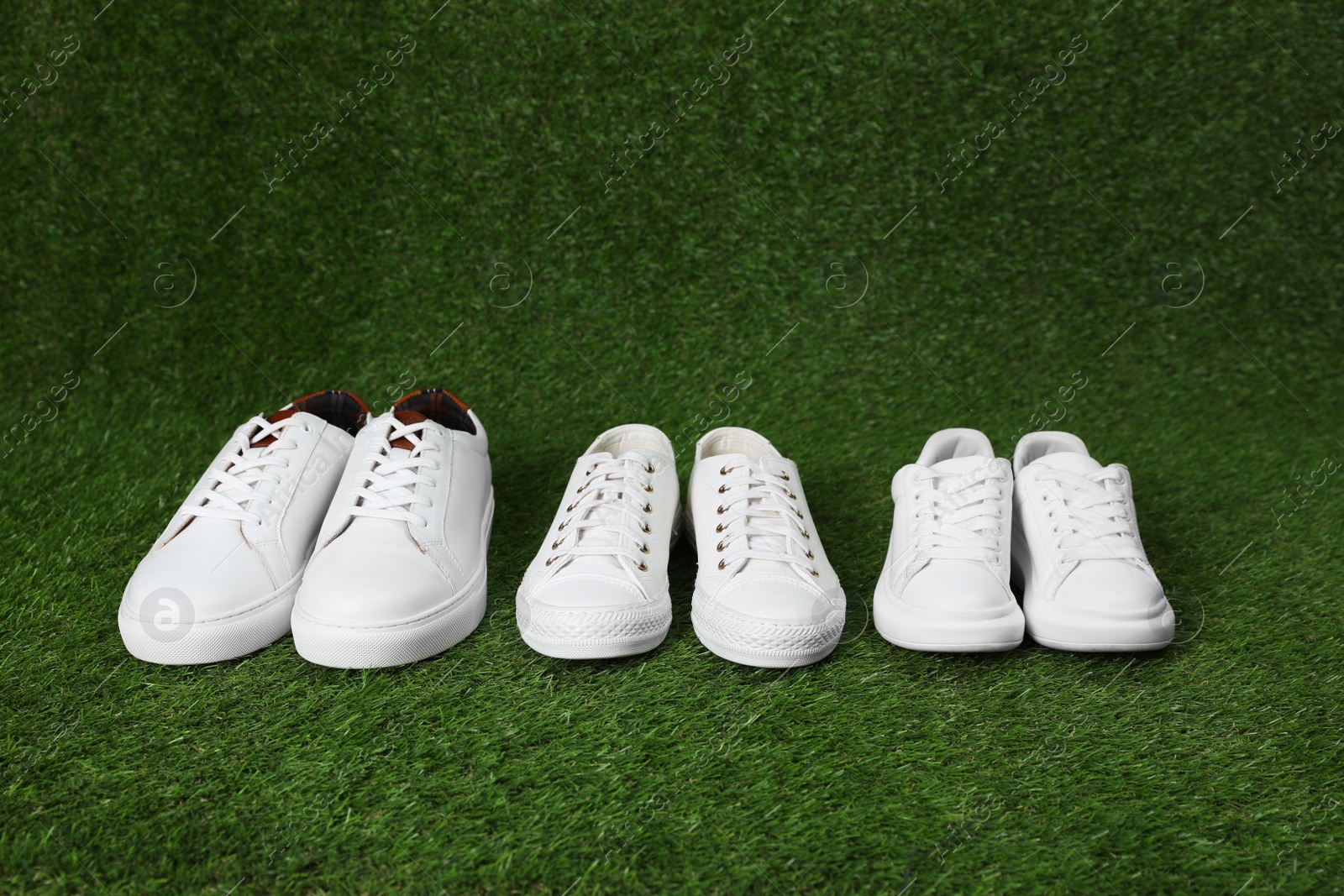 Photo of Stylish sports shoes for all family members on green grass