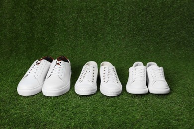 Photo of Stylish sports shoes for all family members on green grass