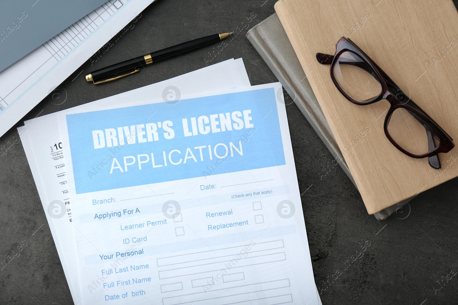 Photo of Driver's license application form, glasses and stationery on grey table, flat lay