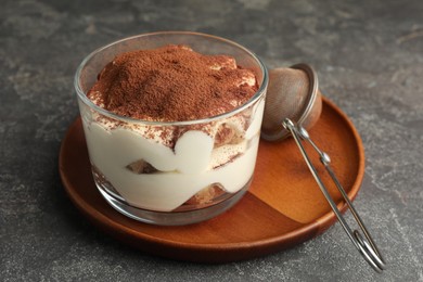 Photo of Delicious tiramisu in glass and sieve with cocoa powder on grey table