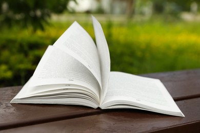 Photo of Open book on wooden table in park