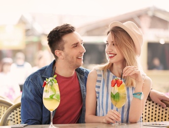 Photo of Young couple with glasses of tasty lemonade in open-air cafe