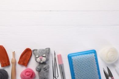 Photo of Felted cat, wool and tools on white wooden table, flat lay. Space for text