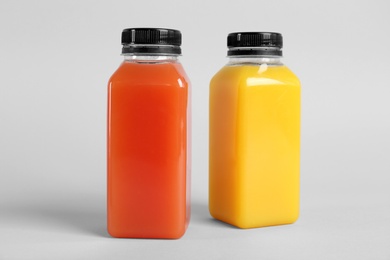 Bottles with delicious colorful juices on light background