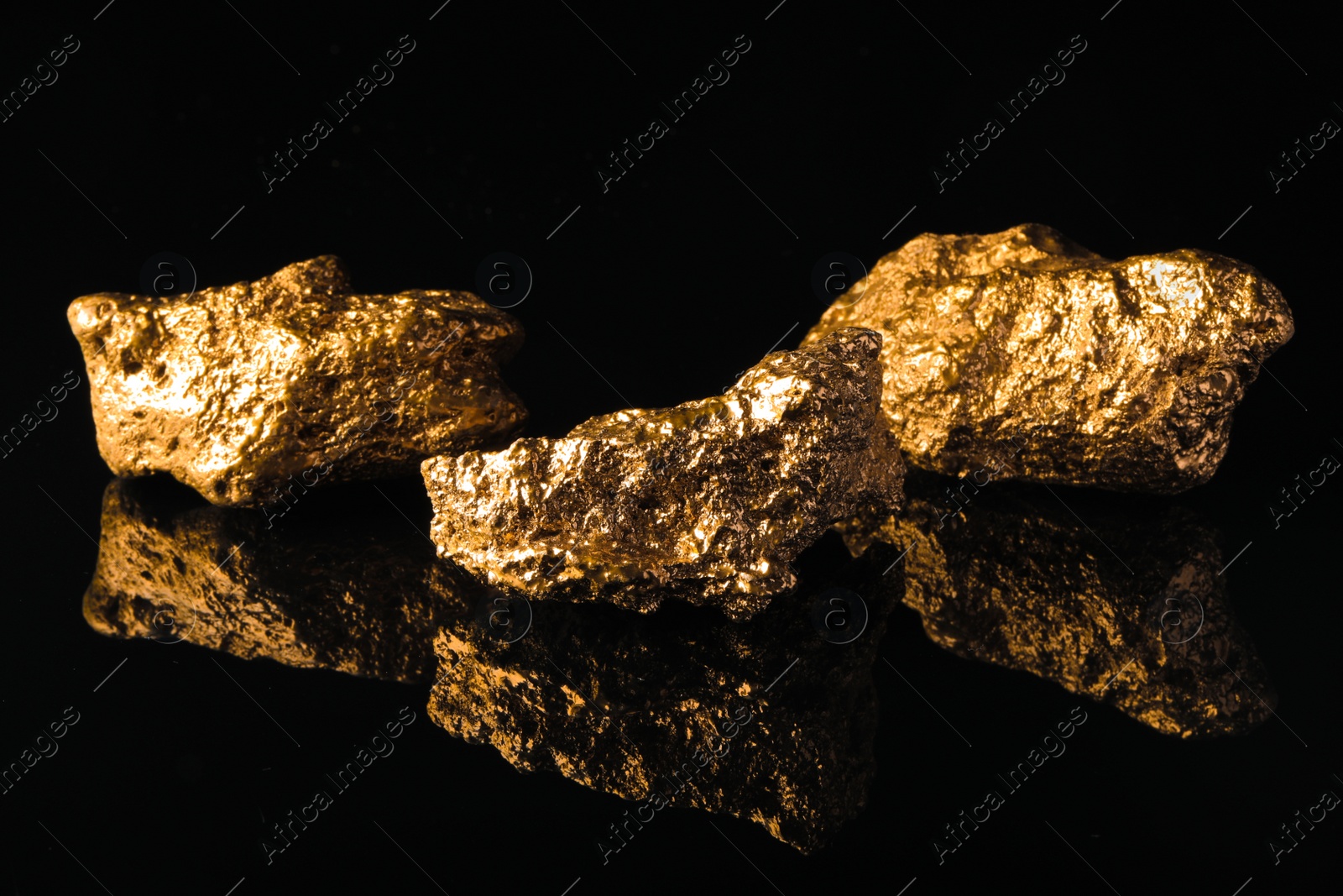 Photo of Beautiful gold nuggets on black reflective surface