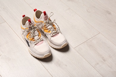 Photo of Pair of sport shoes on wooden floor, space for text