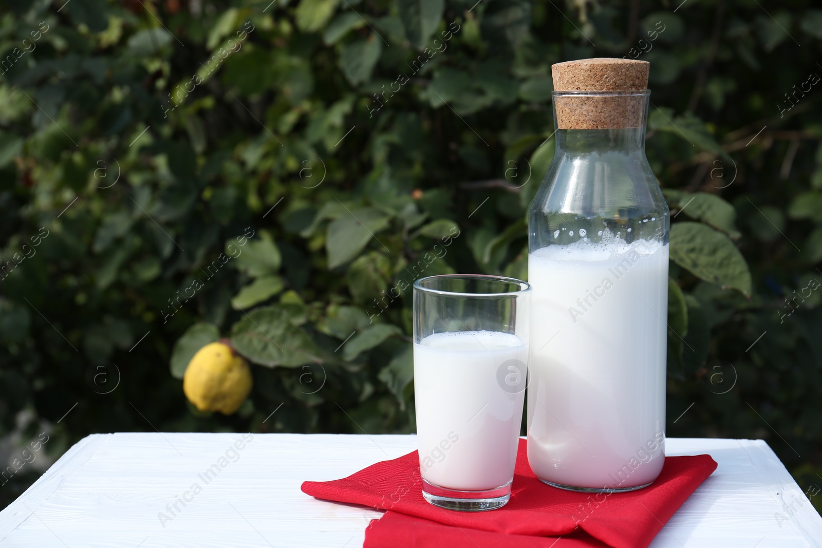 Photo of Glass and bottle of fresh milk on white wooden table outdoors. Space for text
