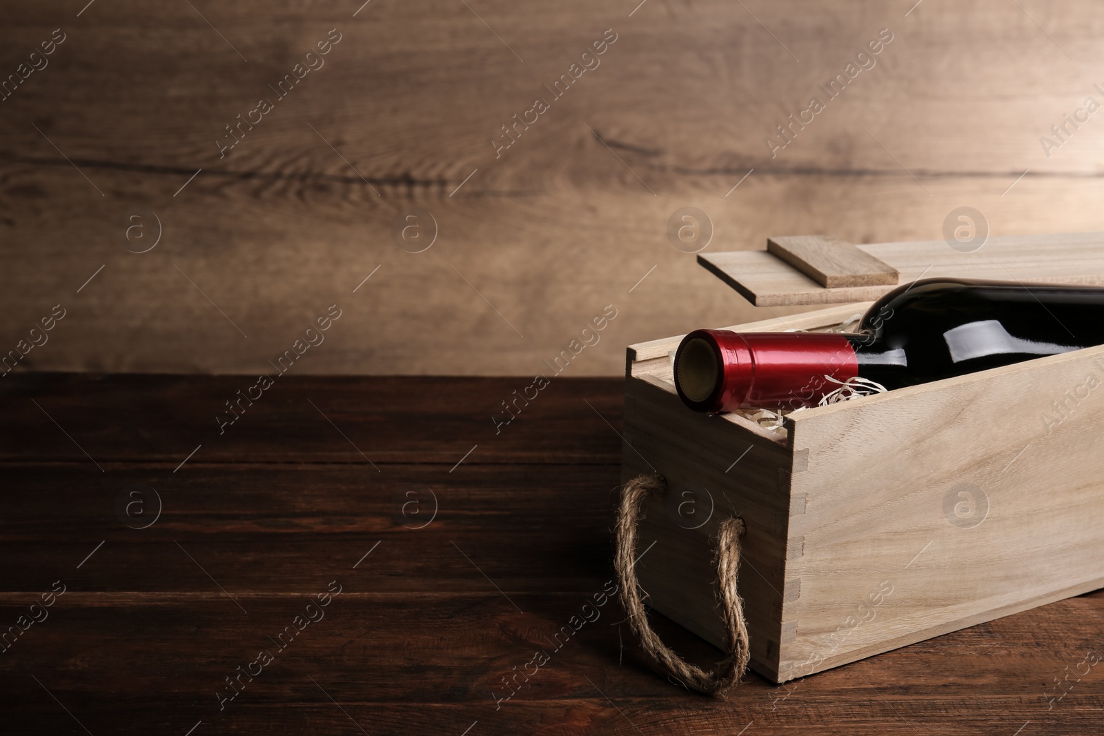 Photo of Open wooden crate with bottle of wine on table, space for text